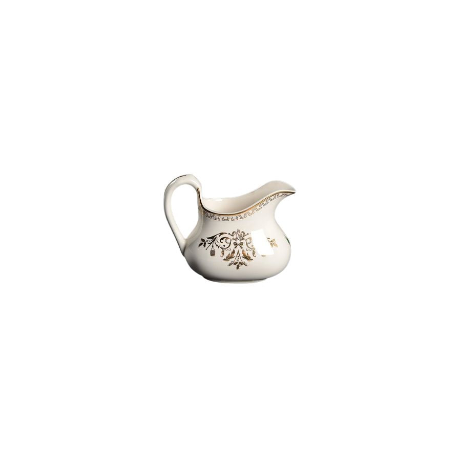 White ceramic creamer with decorative elements on a white background