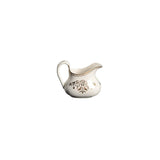 White ceramic creamer with decorative elements on a white background