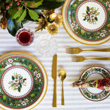 Ivie Page Living's Holly Rose table setting collection: white plate with gold rim, topped with salad plate adorned with holly rose, gold-luster flatware, crystal water and wine glasses.