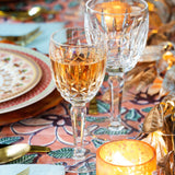 Two stemware crystal wine glasses in candle lit table setting.