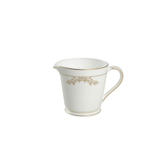 White ceramic creamer with gold floral design on a white background