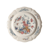 Decorative dinner plate featuring a ase of flowers, fruits, and a bird.