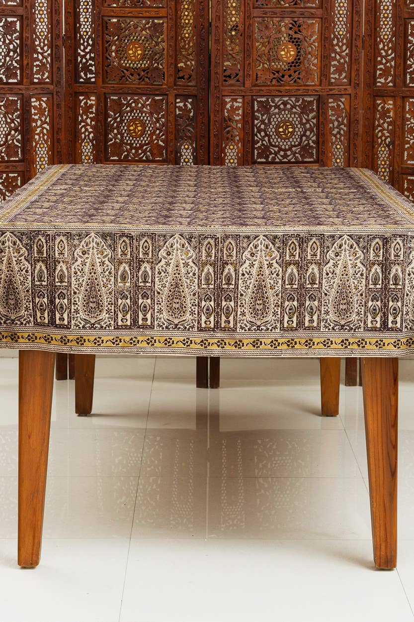 Decorative tablecloth with intricate patterns on a wooden table against a wooden panel background