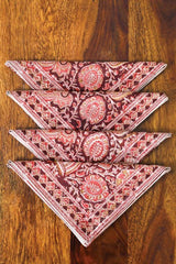 Set of four red and white patterned napkins on a wooden surface